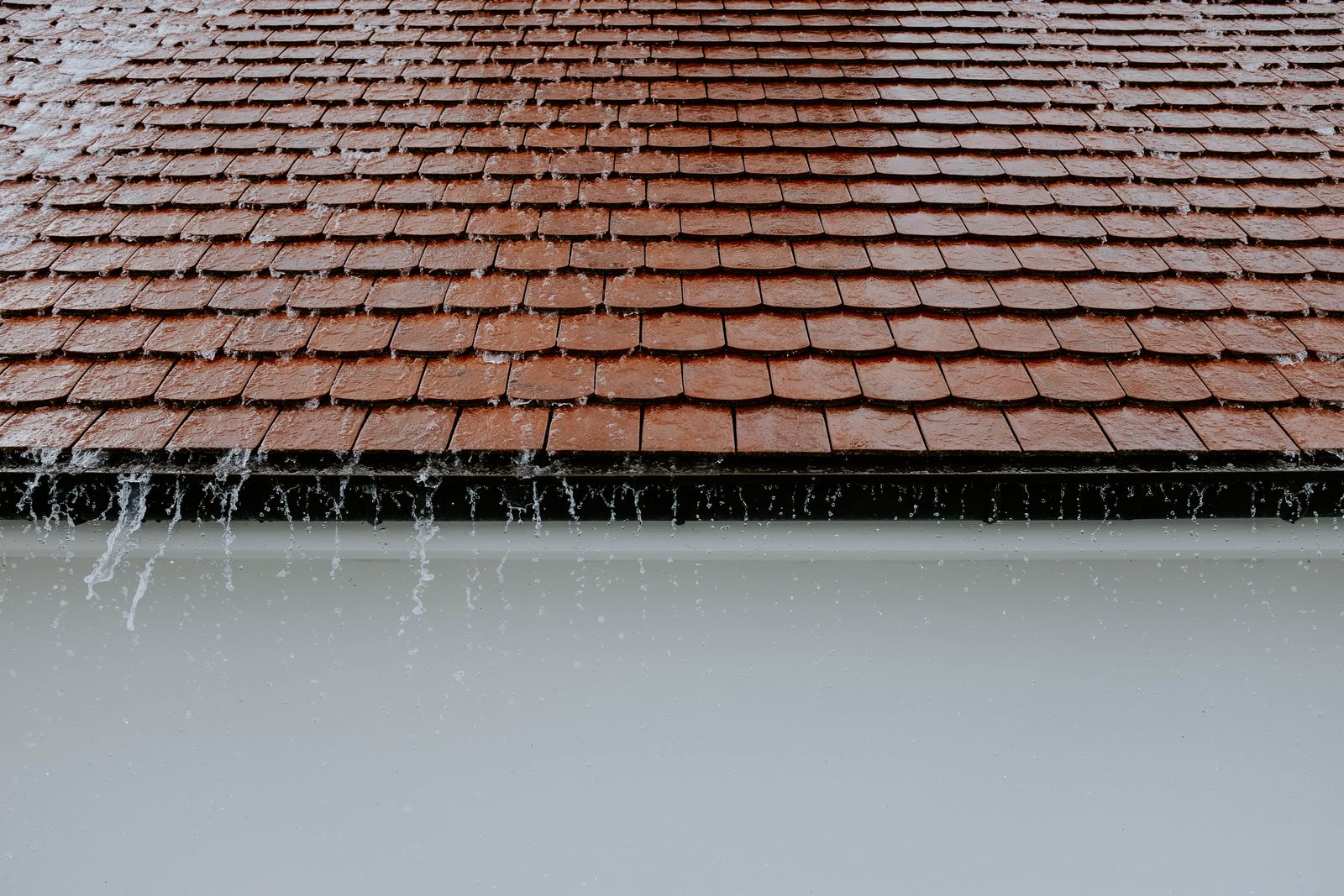 Toiture en tuiles sous la pluie, gouttière et évacuation des eaux pluviales